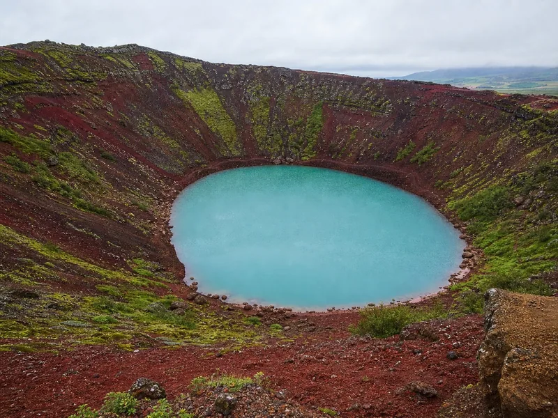 The red scoria rim and green water of Kerið crater